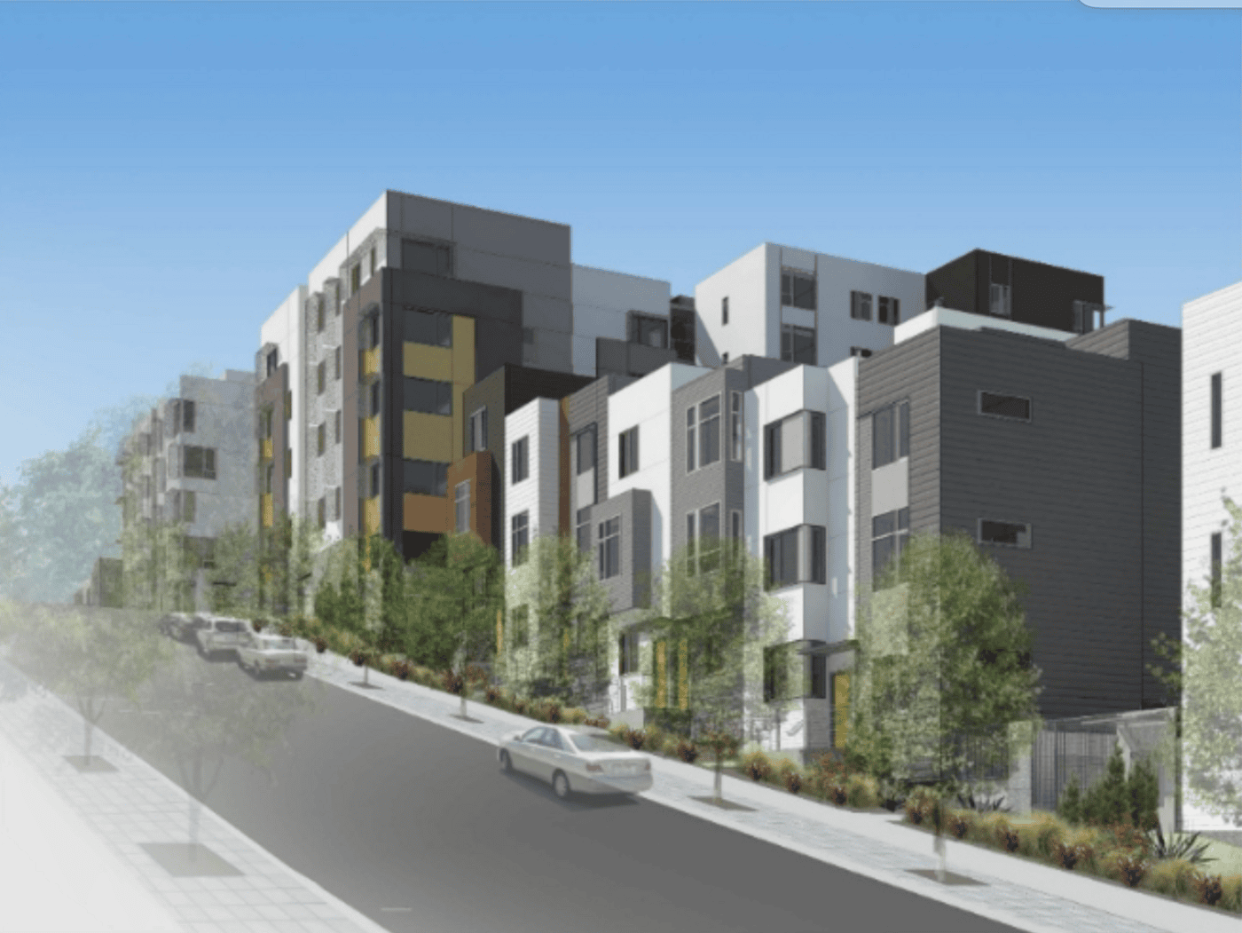 A modern residential street with multi-story apartment buildings and townhouses, lined with young trees and parked cars on a sloped road under a clear blue sky.